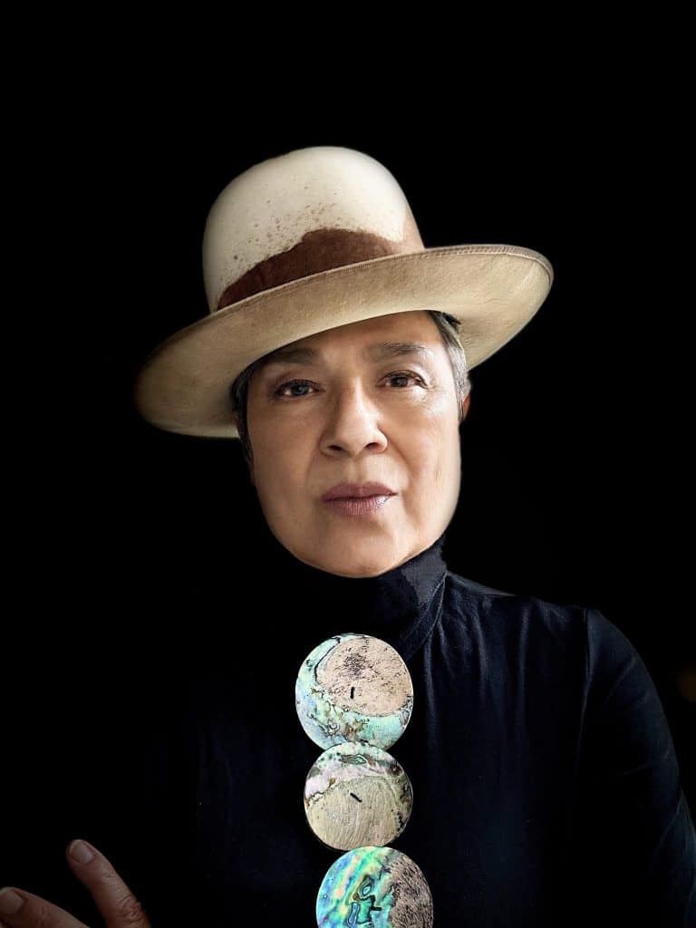 A woman with a straw hat on and silver necklace