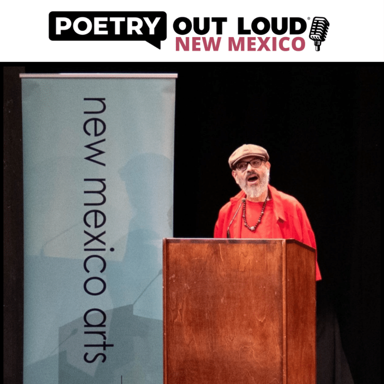 A man with a hat on, wearing a red suit with glasses and a goatee